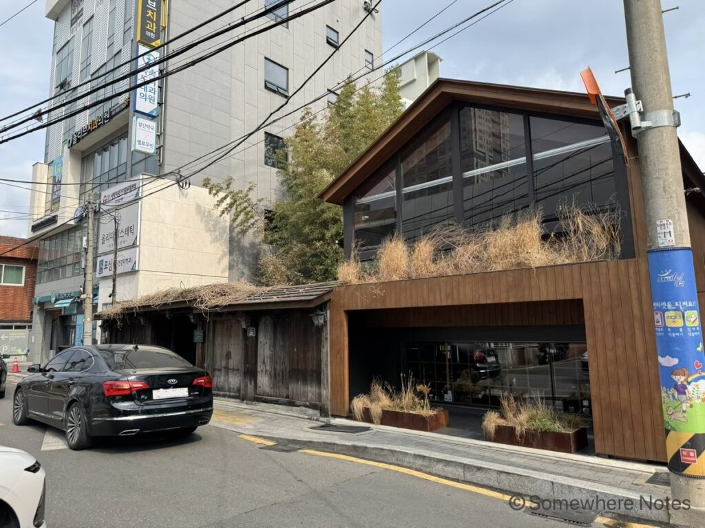 釜山のモモスコーヒー本店の外観。左側には古い木造の門、右側にはガラスと木材を組み合わせたモダンな建物。