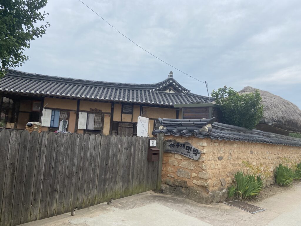 韓国の河回村にある、瓦屋根と藁葺き屋根の伝統的な民泊（韓屋）。石垣と木製の門も見える。