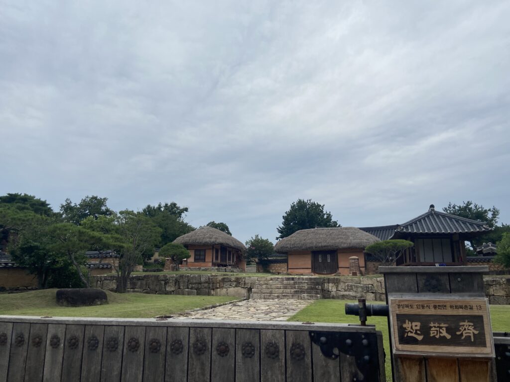 Traditional Hanok houses inside Hahoe Folk Village in Andong, featuring thatched and tiled roofs surrounded by stone walls and a peaceful garden setting.