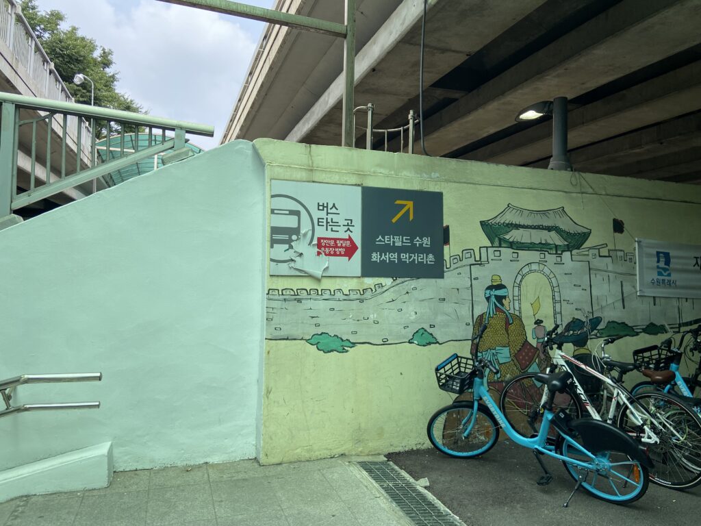 ファソ駅から地下道への階段を降りた場所。スターフィールド水原へ向かう方向を示す案内板。黄色い壁には城壁のイラストがある。