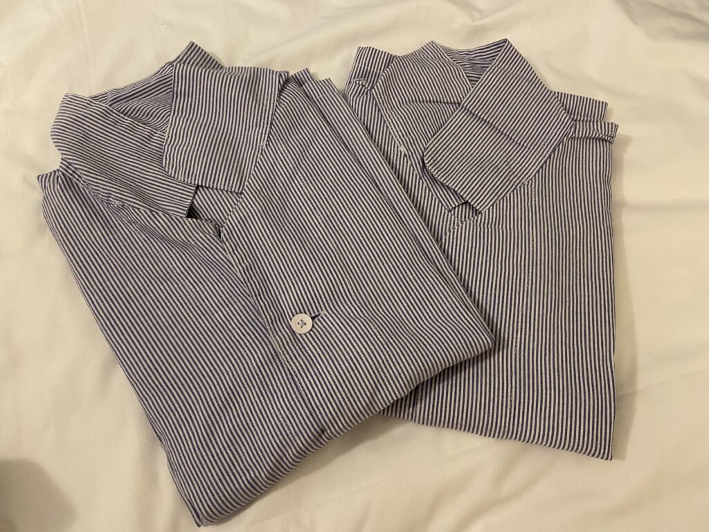 東横インヨンドゥンポの青いストライプ柄の折りたたまれたシャツ型パジャマ。フロント近くに置かれているので自分で持ってくる。白いベッドの上に2枚置かれている様子。