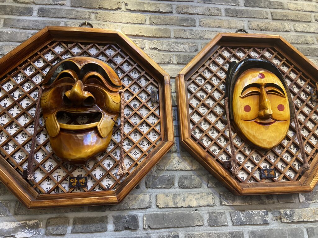 Two traditional Andong Hahoe masks displayed on the interior wall of Shinsegye Jjimdak.