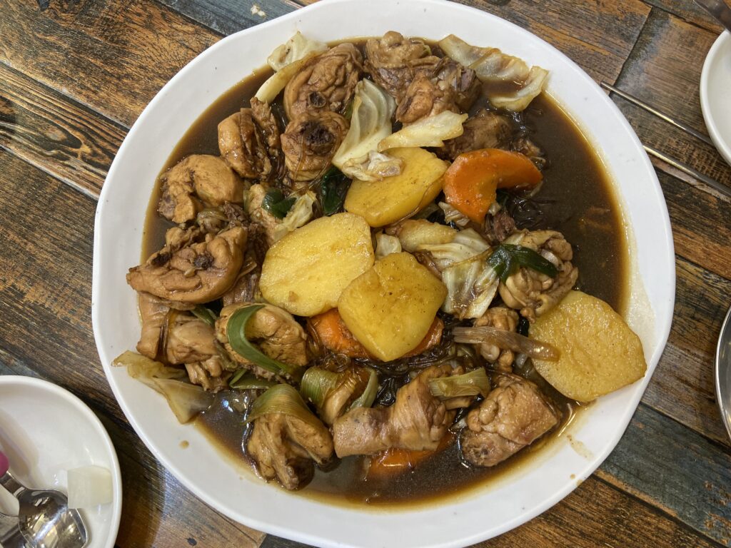 A top-down view of Andong Jjimdak. The dish is served on a white plate with chicken, potatoes, and cabbage evenly arranged, showing the full presentation.