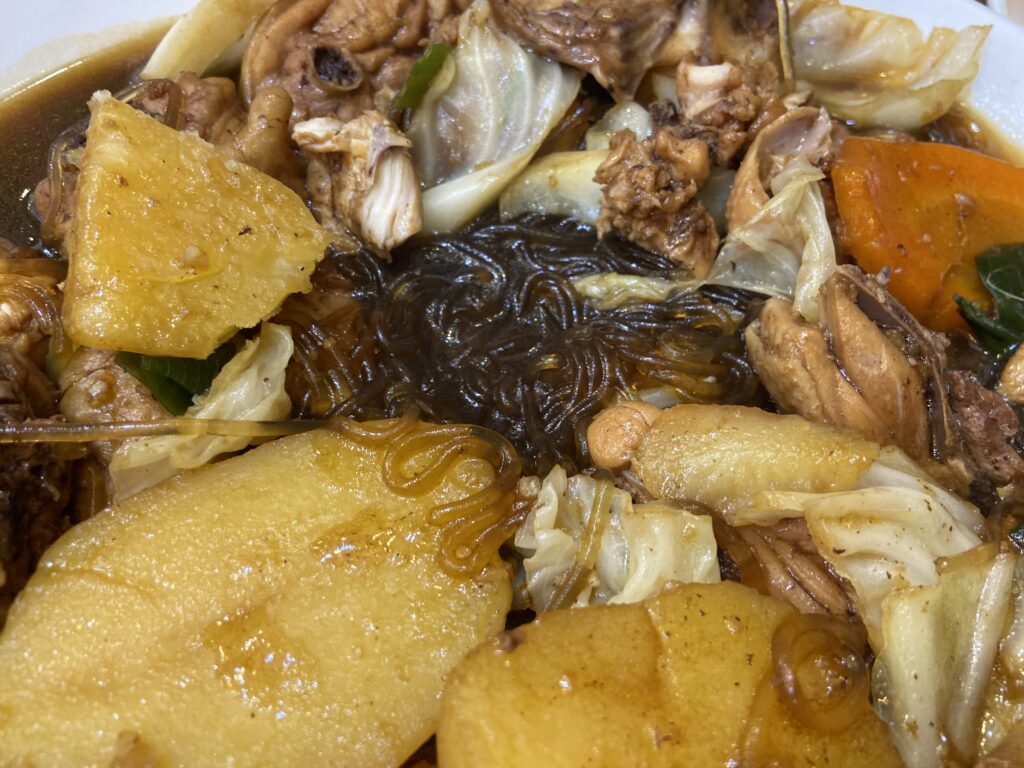 韓国料理アンドンチムタクのクローズアップ画像。醤油タレが絡んだ韓国のタンミョンという春雨、大きなジャガイモの断面が目立っている。